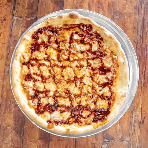 A whole IPIZZA BBQ chicken pizza with melted cheese and sauce on a metal pan.